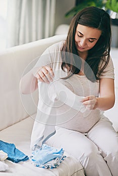 Pregnant, woman and happy with clothes on sofa for newborn attire or apparel, folding and organizing for arrival of baby