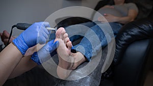 Pregnant woman on a hardware pedicure procedure in a beauty salon.