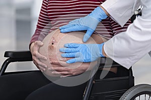 Pregnant woman has her belly checked by a doctor& x27;s hands