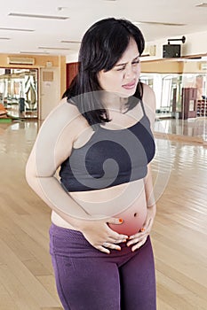 Pregnant woman having contraction in fitness center photo