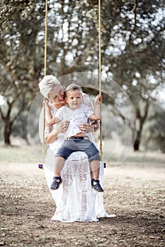 Pregnant woman having fun with her toddler son on the swing