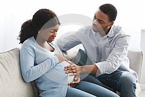 Pregnant woman having labor pains, sitting with husband on couch