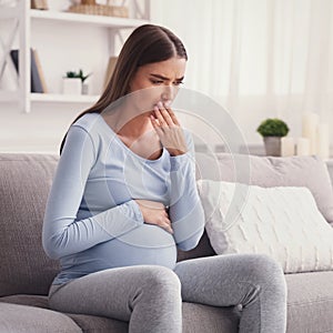 Pregnant Woman Having Pregnancy Morning Sickness Sitting On Couch