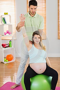 Pregnant woman having relaxing massage while sitting on exercise ball