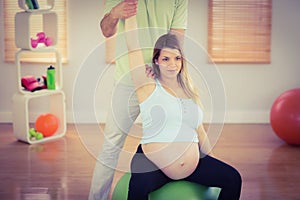 Pregnant woman having relaxing massage while sitting on exercise ball