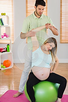 Pregnant woman having relaxing massage while sitting on exercise ball