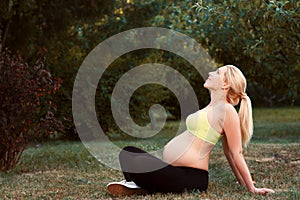 Pregnant woman having sunbath outdoor, free space
