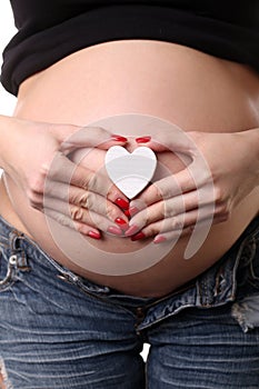 Pregnant woman with heart symbol. Close up. White background