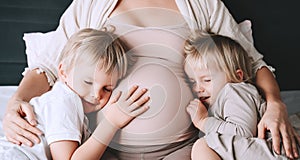 Pregnant woman with her children at home. Third pregnancy. Maternity, family, parenting concept