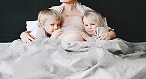 Pregnant woman with her children at home. Third pregnancy. Maternity, family, parenting concept
