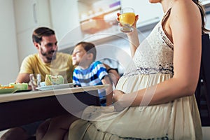 Pregnant woman and her family breakfasting in the kitchen