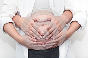 Pregnant woman and her handsome husband hugging the tummy in home