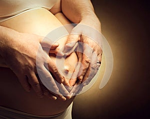 Pregnant woman and her husband caressing her belly