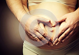 Pregnant woman and her husband caressing her belly