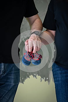 Pregnant woman and her husband, hold baby shoes in their hands