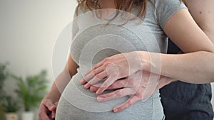 Pregnant woman and her husband holding hand together. Family is happy in anticipation of baby.