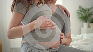 Pregnant woman and her husband holding hand together. Family is happy in anticipation of baby.