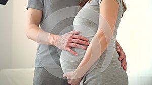 Pregnant woman and her husband holding hand together. Family is happy in anticipation of baby.