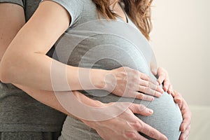 Pregnant woman and her husband holding hand together. Family is happy in anticipation of baby.