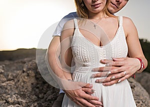 Pregnant woman and her husband holding hands on tummy