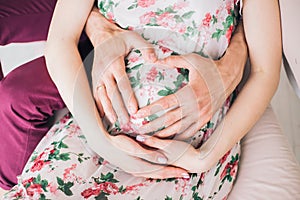 Pregnant woman and her husband hugging beautiful round big belly with hand