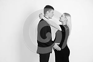 Pregnant woman and her husband hugging and holding onto your stomach in black clothes on a white background. Black and white