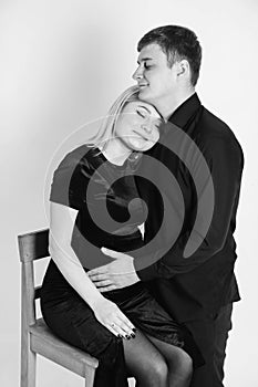 Pregnant woman and her husband hugging and holding onto your stomach in black clothes on a white background. Black and white