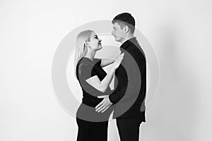 Pregnant woman and her husband hugging and holding onto your stomach in black clothes on a white background. Black and white