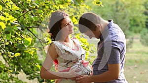 Pregnant woman and her husband hugging in the Park