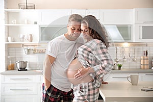 Pregnant woman with her husband in kitchen.