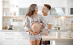 Pregnant woman with her husband in kitchen.