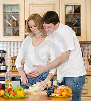 Pregnant woman and her husband in kitchen cook food