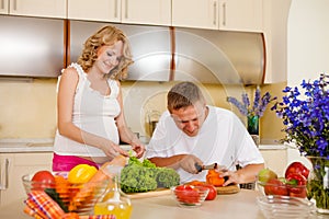 Pregnant woman and her husband prepare vegetable salad