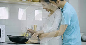 Pregnant woman and her husband preparing healthy food together in kitchen at home.