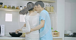 Pregnant woman and her husband preparing healthy food together in kitchen at home.