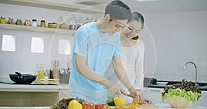 Pregnant woman and her husband preparing healthy food together in kitchen at home.