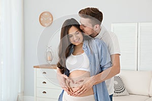 Pregnant woman and her husband showing heart with hands