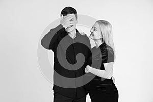 Pregnant woman and her husband smiling in black clothes on a white background. Black and white picture. Beautiful married couple.