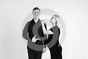 Pregnant woman and her husband smiling in black clothes on a white background. Black and white picture. Beautiful married couple.