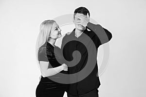 Pregnant woman and her husband smiling in black clothes on a white background. Black and white picture. Beautiful married couple.