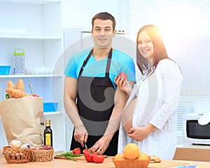 Pregnant woman and her husband standing together in the kitchen