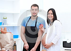 Pregnant woman and her husband standing together in the kitchen