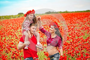 Pregnant woman her husband and their daughter in poppy field