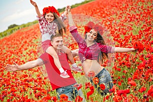 Pregnant woman her husband and their daughter in poppy field