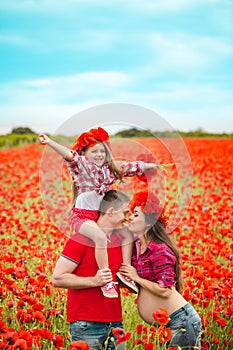 Pregnant woman her husband and their daughter in poppy field