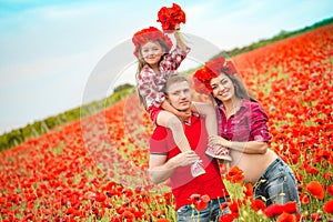 Pregnant woman her husband and their daughter in poppy field