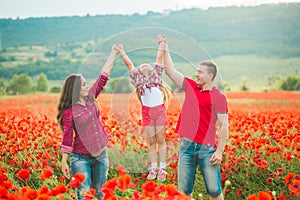 Pregnant woman her husband and their daughter in poppy field