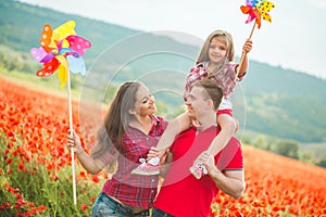 Pregnant woman her husband and their daughter in poppy field