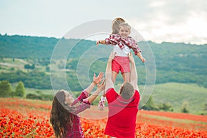 Pregnant woman her husband and their daughter in poppy field