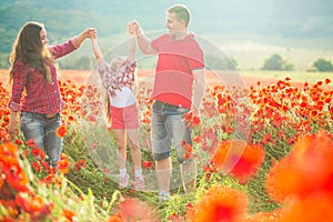 Pregnant woman her husband and their daughter in poppy field